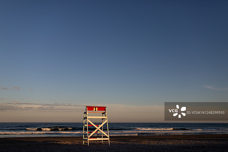 日落时分，救生员坐在空旷的海滩上图片素材