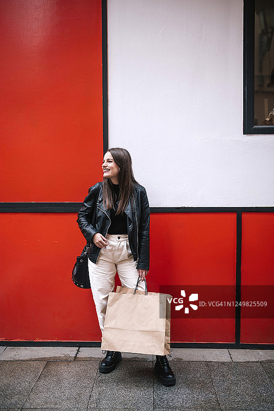 快乐的年轻女人在城市里拿着购物袋图片素材