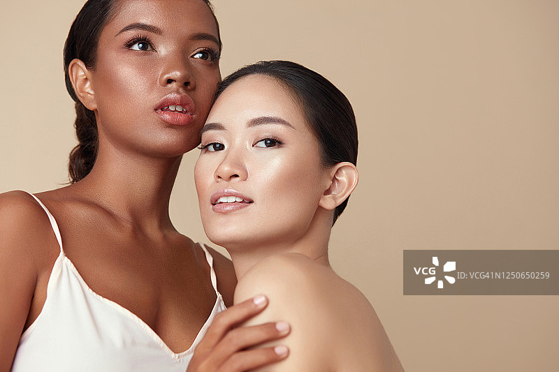 美。不同的模特肖像与广告复制空间。温柔的亚洲和混合种族妇女一起摆姿势在米色背景。拥有完美肌肤和自然妆容的女性。图片素材