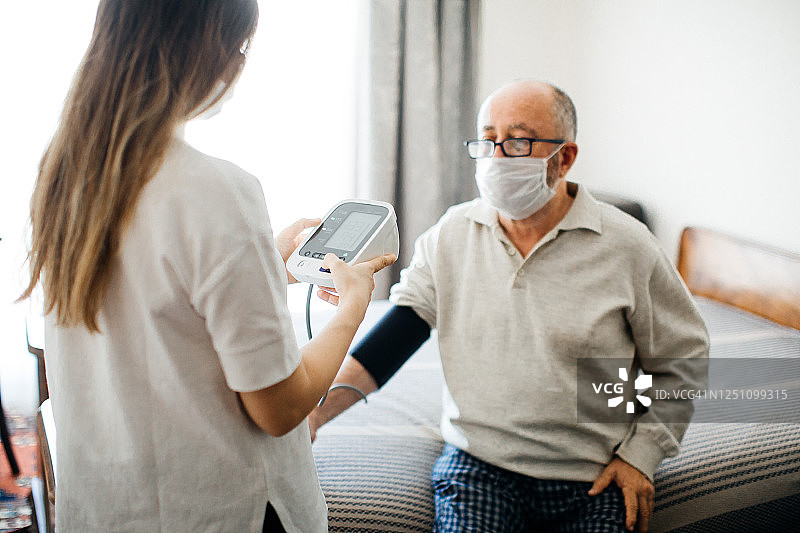 护士在家为一位老人检查血压图片素材