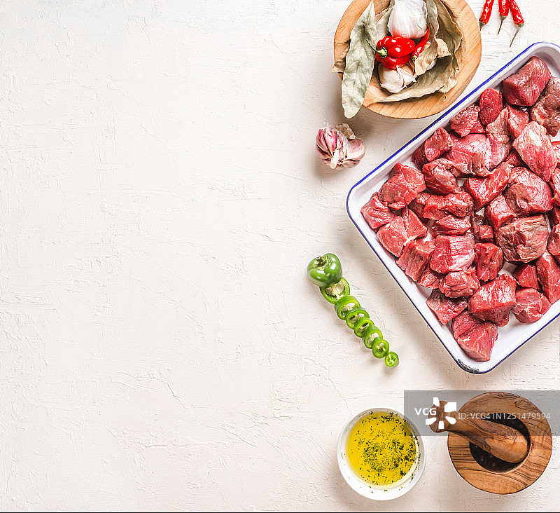 肉类食品的布局。将生肉切成小块放在烤盘上，加入香草、墨西哥胡椒、橄榄油、研钵和调味料。图片素材