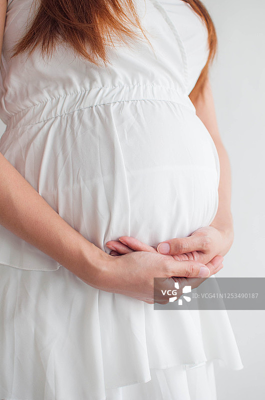 一个白人背景的年轻怀孕的东南亚妇女图片素材