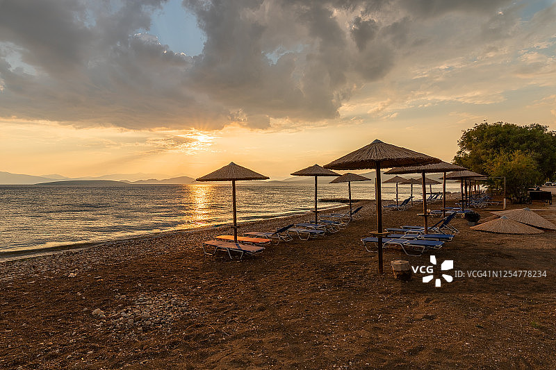 日落时，海滩上的空椅子和雨伞图片素材