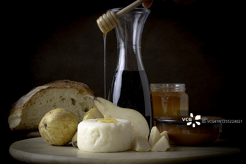 切菜板上放着奶酪、梨、面包、蜂蜜和红酒图片素材