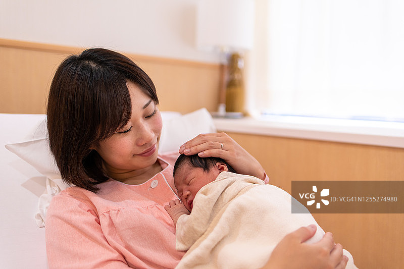 年轻母亲抱着刚出生的婴儿在医院图片素材