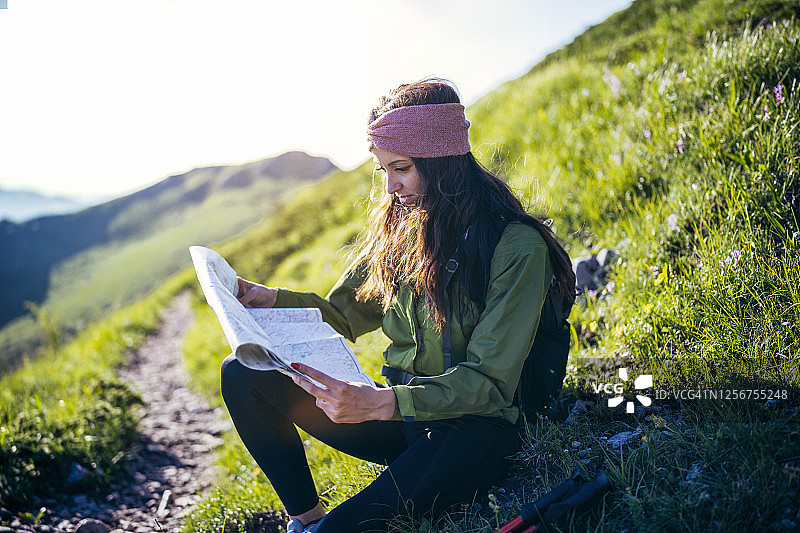 女性徒步旅行者在山里阅读地图。图片素材
