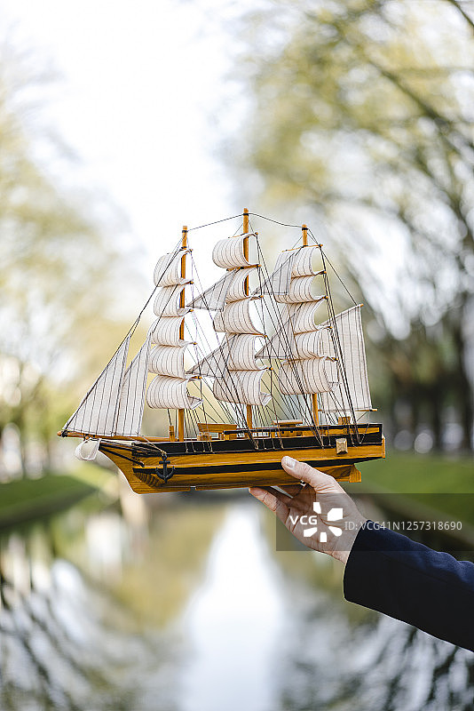 在海峡上，一个人拿着模型船的手图片素材