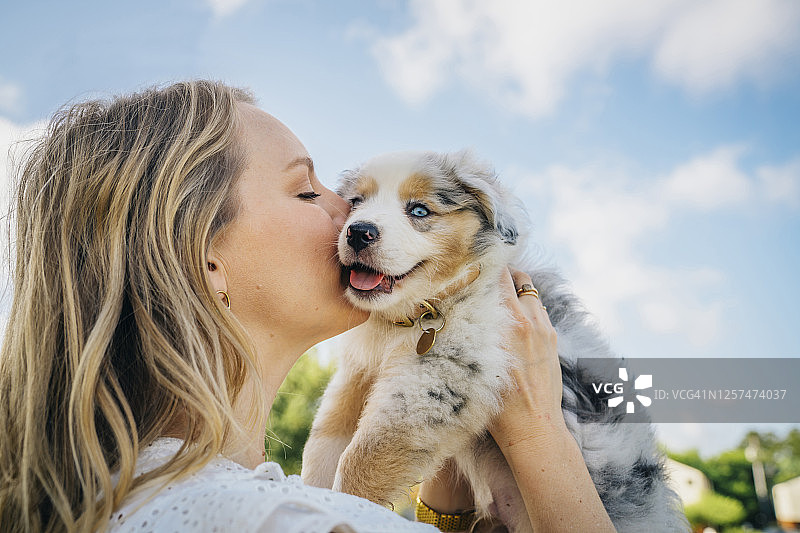 一名女子亲吻澳大利亚小狗的脸颊图片素材