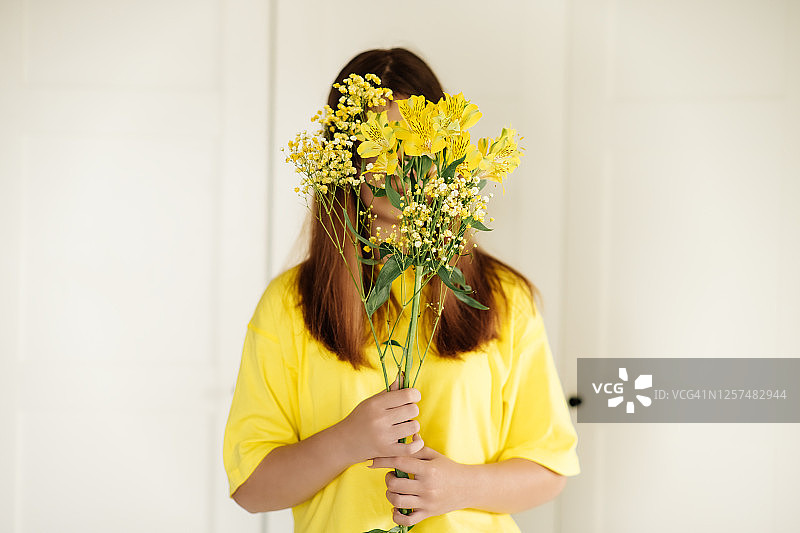 一个小女孩拿着一束黄花。图片素材