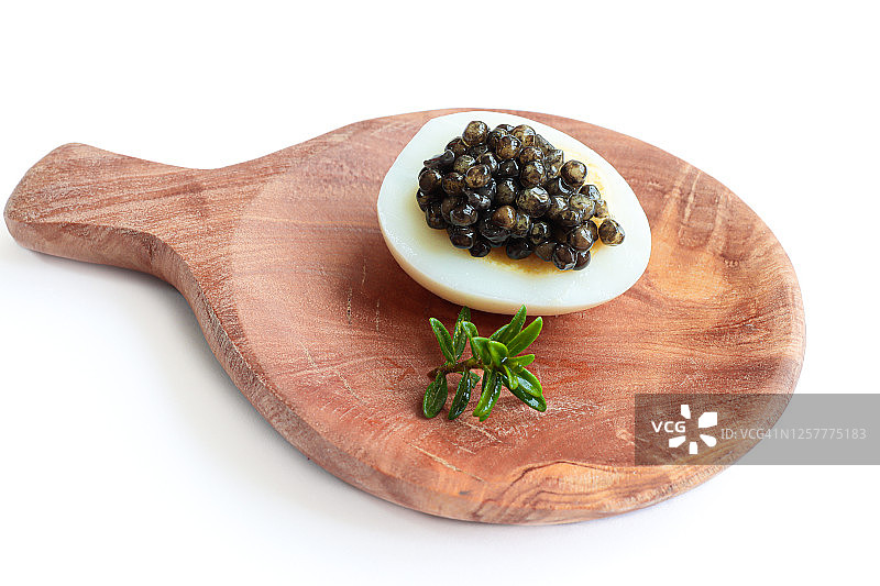 美食佳肴，美味的黑鲟鱼子酱放在鹌鹑蛋的木盘上图片素材