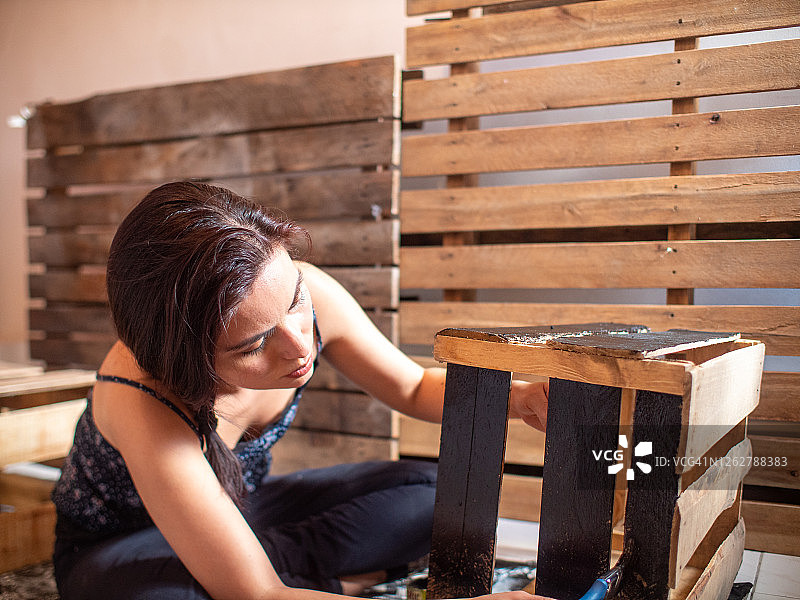 年轻的西班牙妇女穿着深色的衣服画一个木制的盒子，在一个托盘的背景图片素材