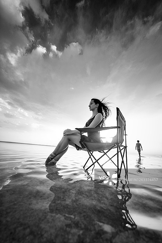 舞女坐在湖上的日光浴床上图片素材