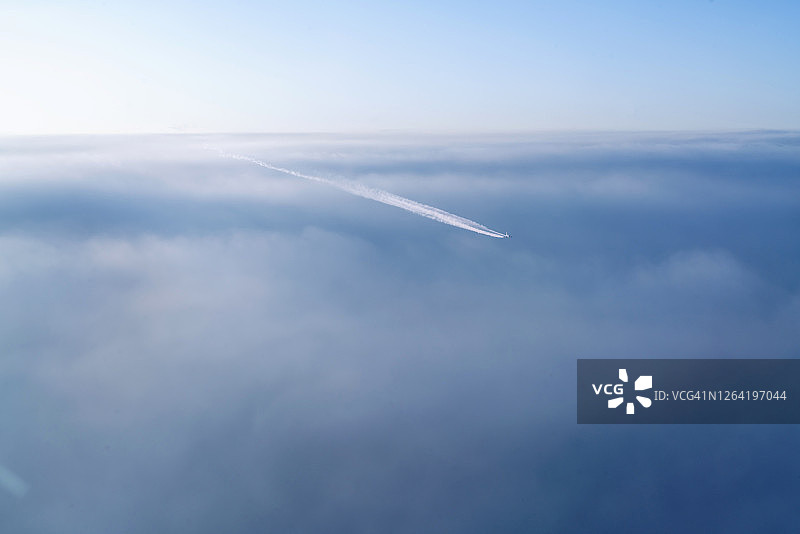 云带着飞机飞过天空，喷出白色的燃油烟线图片素材