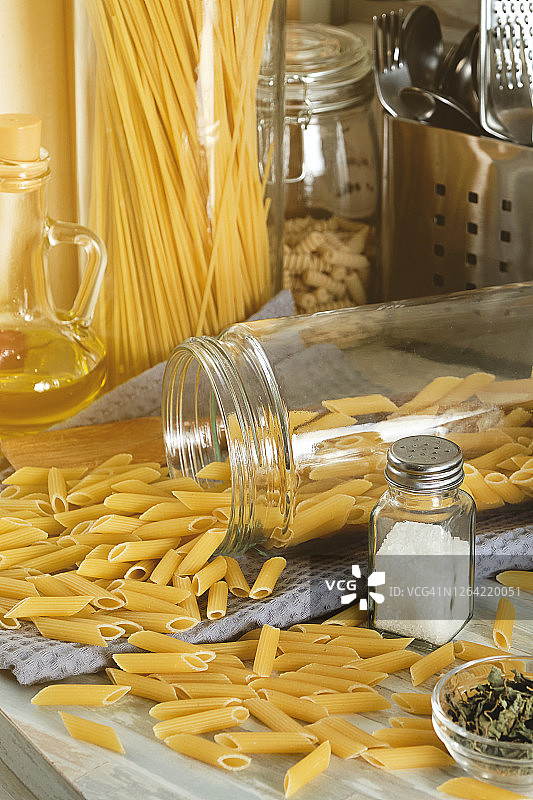 在家里用奶油酱和罗勒烹饪意大利面。选择的通心粉。生通心粉通心粉在一个玻璃储存罐，在厨房的桌子上。素食。一步一步的指导，自己做。步骤1。图片素材