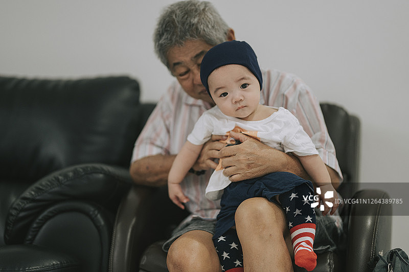 一个活跃的亚洲华人老人，抱着孙子照顾孩子，有一段亲密的时光图片素材