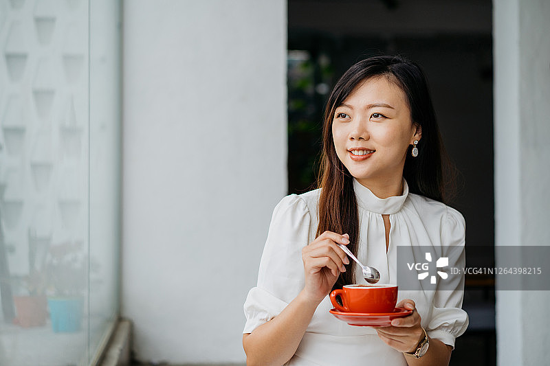 年轻的亚洲女人拿着红色的咖啡杯碟图片素材