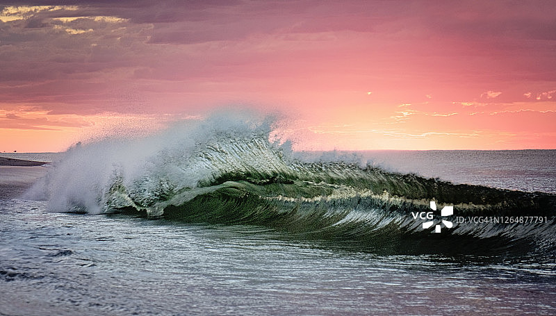 在长岛的琼斯海滩，粉红色的天空映衬着美丽的波浪图片素材