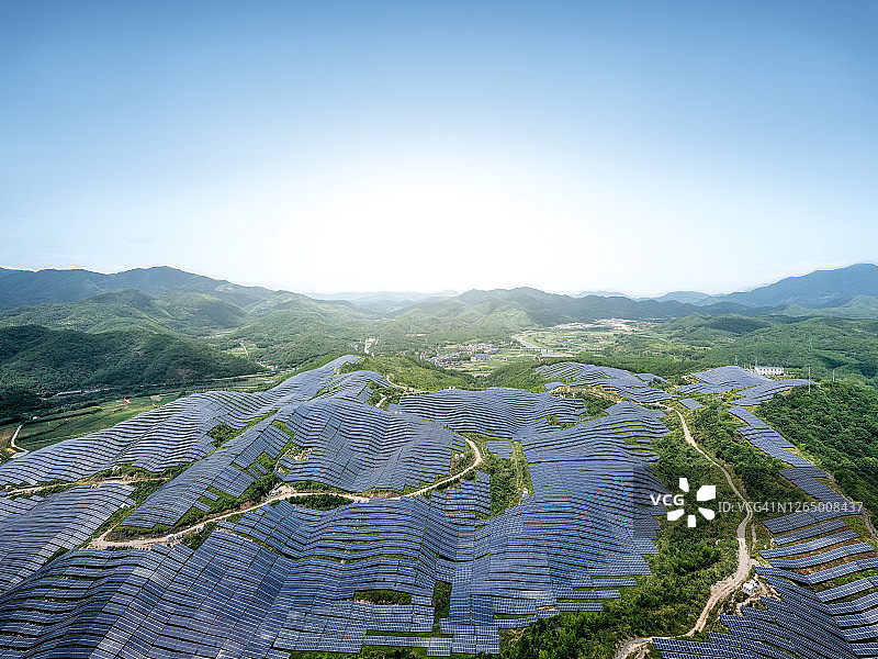 绵延起伏的山丘上壮丽的太阳能发电站的鸟瞰图图片素材