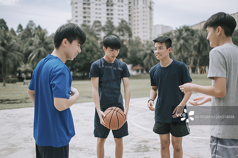 一群十几岁的亚裔中国男孩正在为一场篮球比赛做准备，他们把球队分开练习图片素材