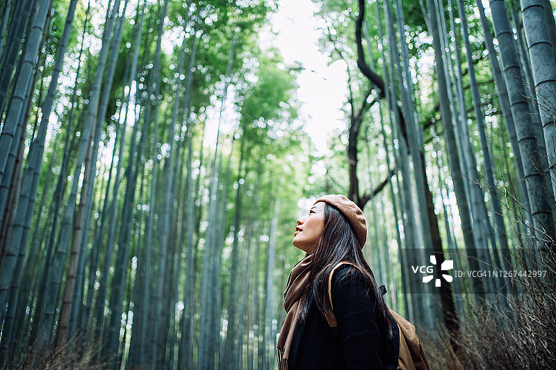 年轻的亚洲女背包客享受大自然。新冠肺炎疫情期间，在乡村的竹林里，深呼吸新鲜空气，放松散步图片素材