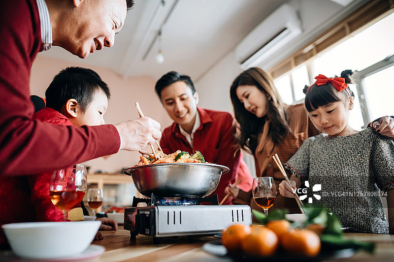 低角度观看三代快乐的亚洲家庭庆祝中国新年和享受美味的传统中国汤菜团圆饭图片素材