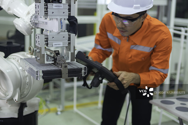 工程师利用机器人的控制面板进行编程，并将数据输入到Smart工厂的机器人手臂控制器中图片素材