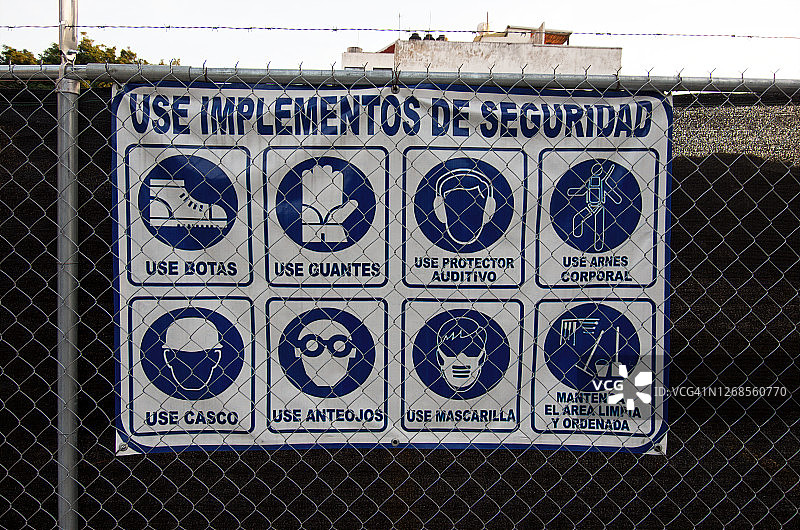在建筑工地周围的铁丝网上，用西班牙语写着“使用安全设备”(Use implementos de seguridad)图片素材