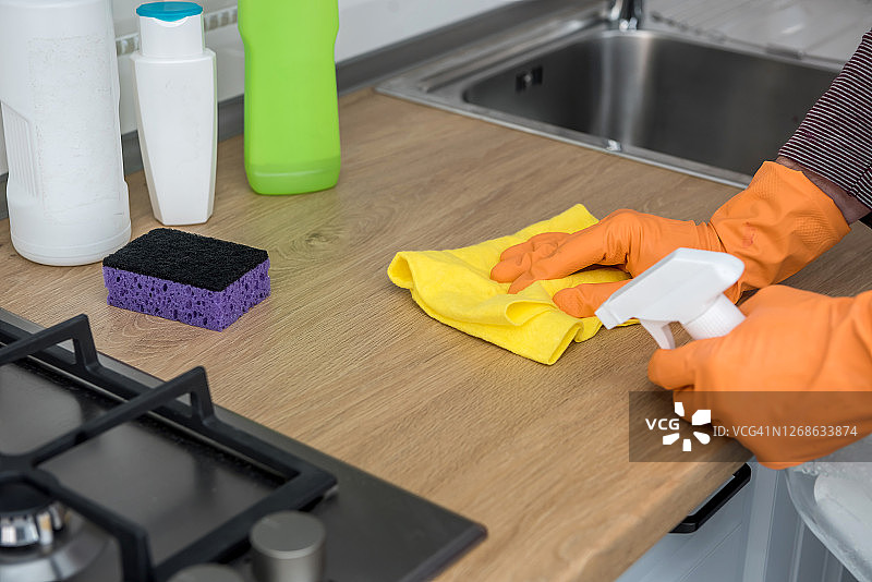将橙色防护手套与抹布清洗和喷雾剂清洁厨房家具图片素材