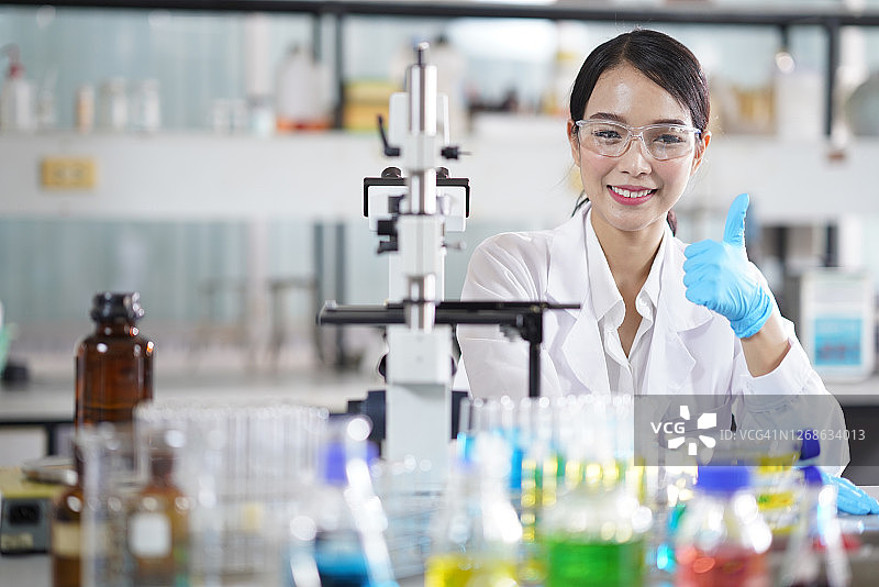 年轻自信的女科学家坐在化学实验室的肖像图片素材