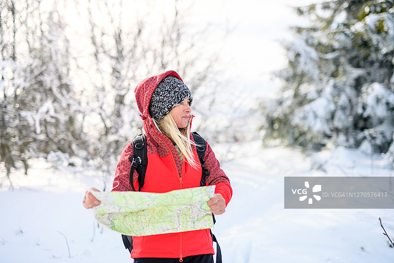肖像妇女远足在雪覆盖的冬季自然，使用地图。图片素材
