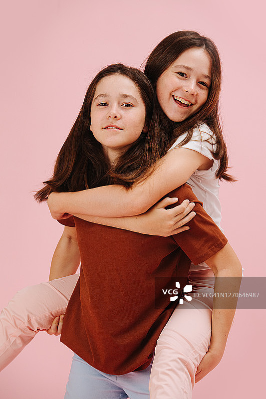 一对漂亮的双胞胎姐妹快乐地在一起玩，一个骑着另一个图片素材