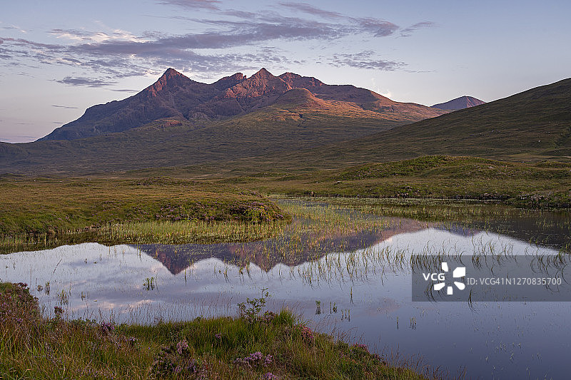 库林山脉的全景反映在平静的水在斯凯岛的小湖南艾琳，苏格兰。美丽的自然和风景在日落图片素材