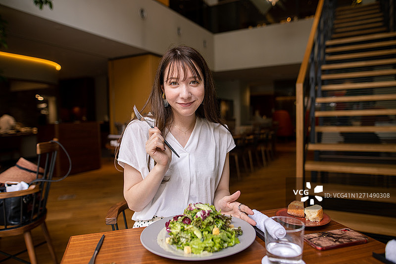 年轻女子在餐厅午餐吃沙拉的肖像图片素材