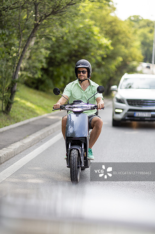 英俊而专注的男人正在城市里驾驶他的电动滑板车图片素材
