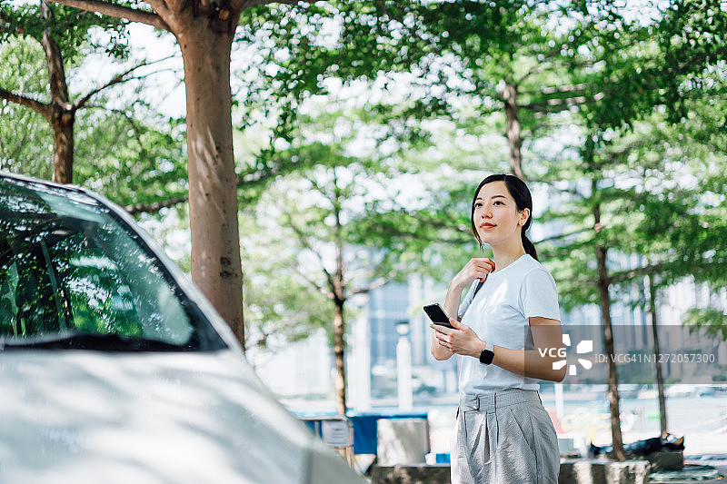 年轻的亚洲女性在早上开车上班时带着智能手机。动态业务的概念图片素材