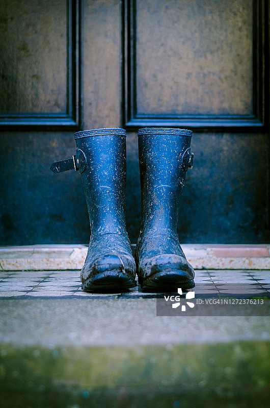 前门台阶上的肮脏泥泞的雨靴图片素材