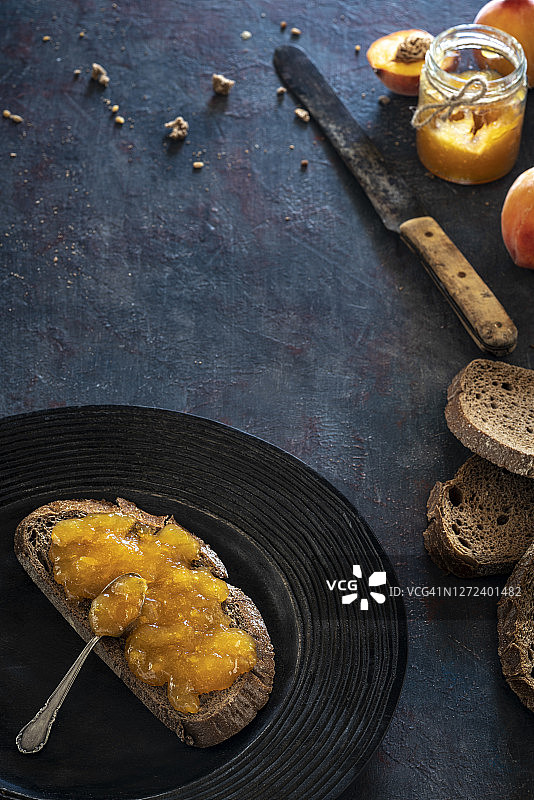 桃子酱涂在全麦面包片上，背景是乡村的黑色图片素材