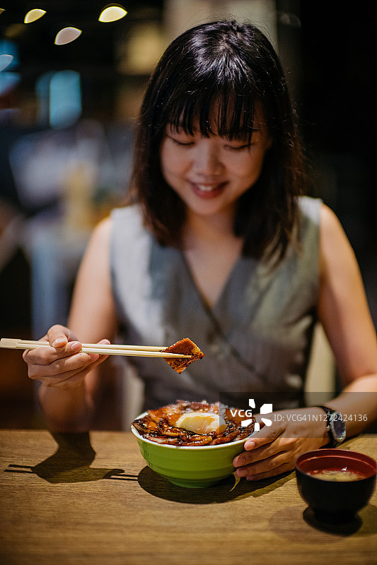 年轻的亚洲妇女吃日本烤猪肉饭碗图片素材
