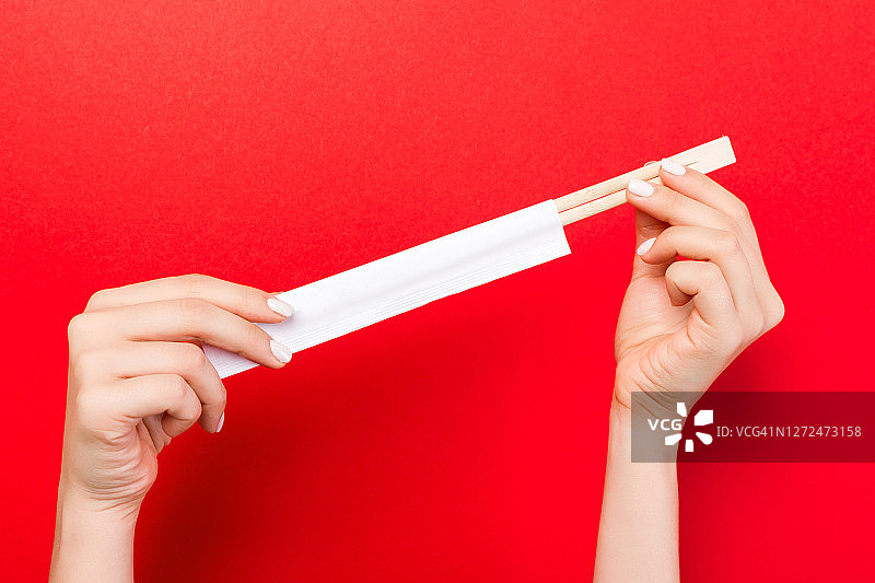 裁剪图像的两个女人的手拿着筷子在红色的背景。准备吃概念与复制空间图片素材