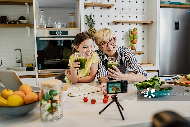 一位年长的女士正在和孙女拍摄关于健康饮食的视频博客图片素材