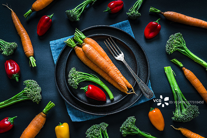 纯素饮食概念:新鲜的有机蔬菜盘子从上面拍摄在黑暗的背景图片素材