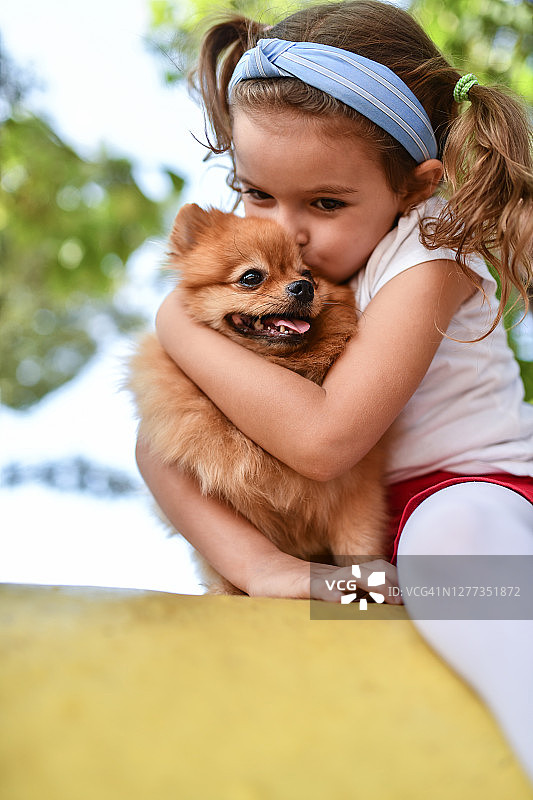 可爱的女孩拥抱和亲吻她的小狗图片素材