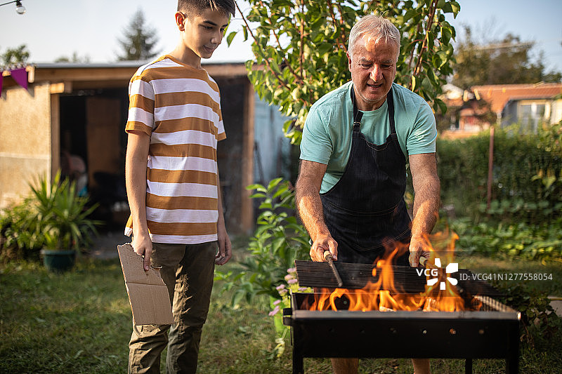 祖父在后院教孙子如何做烧烤图片素材