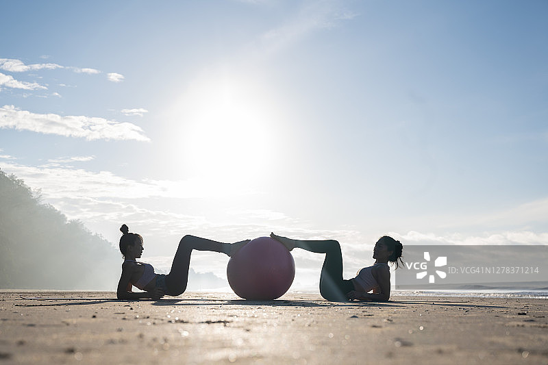 两个女人早上在海滩上练瑜伽图片素材