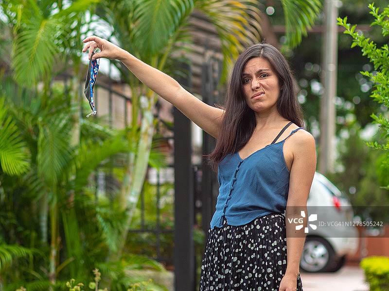 一位拉丁/西班牙裔的年轻女子正拿着一个即将被扔掉的蓝花手工面膜图片素材