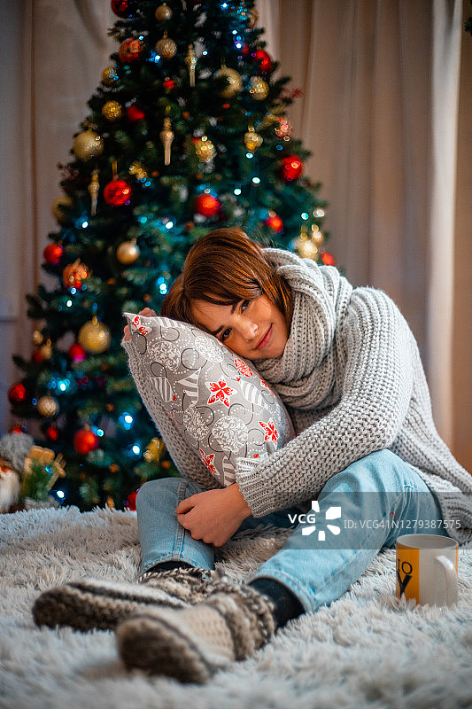 美丽的女孩在一个温暖的毛衣微笑和看着镜头在圣诞节图片素材