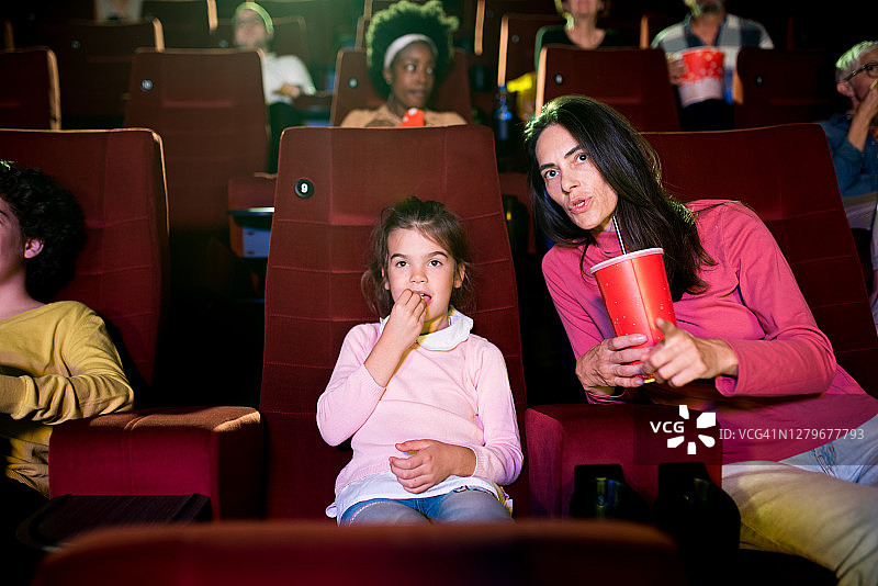 妈妈在电影院给她的小女儿解释电影图片素材
