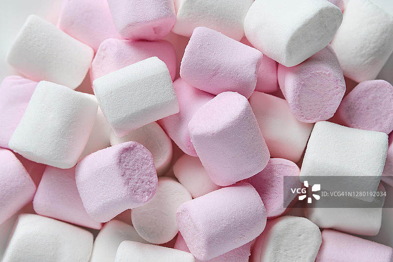甜美轻盈的粉白色棉花糖躺在盘子上，粉红色的背景。食品的背景。图片素材