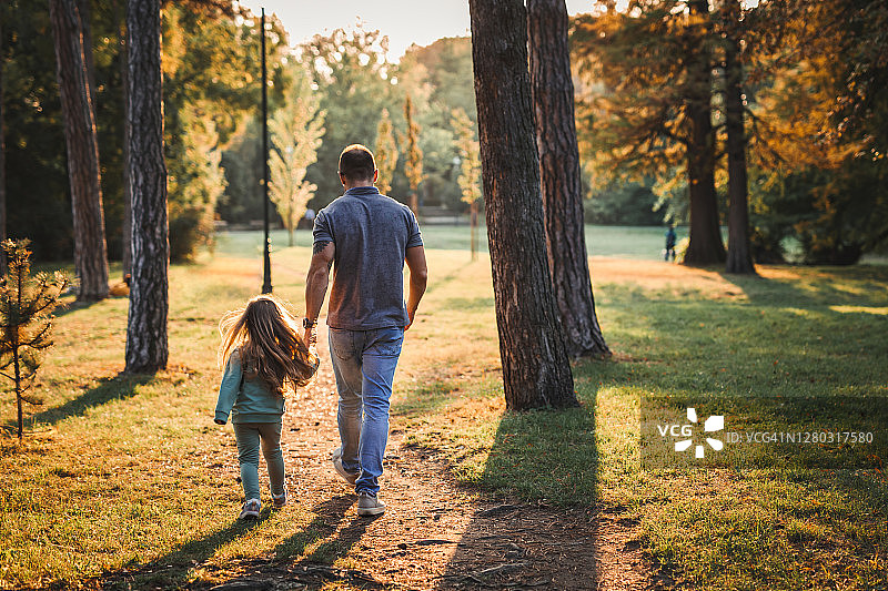 日落时分，父亲和女儿在公园散步图片素材
