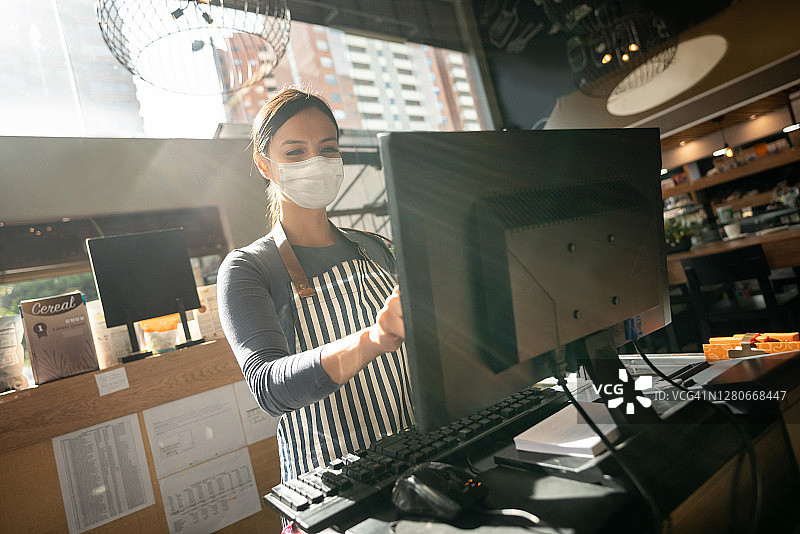 在咖啡馆工作的带着面罩的女人图片素材